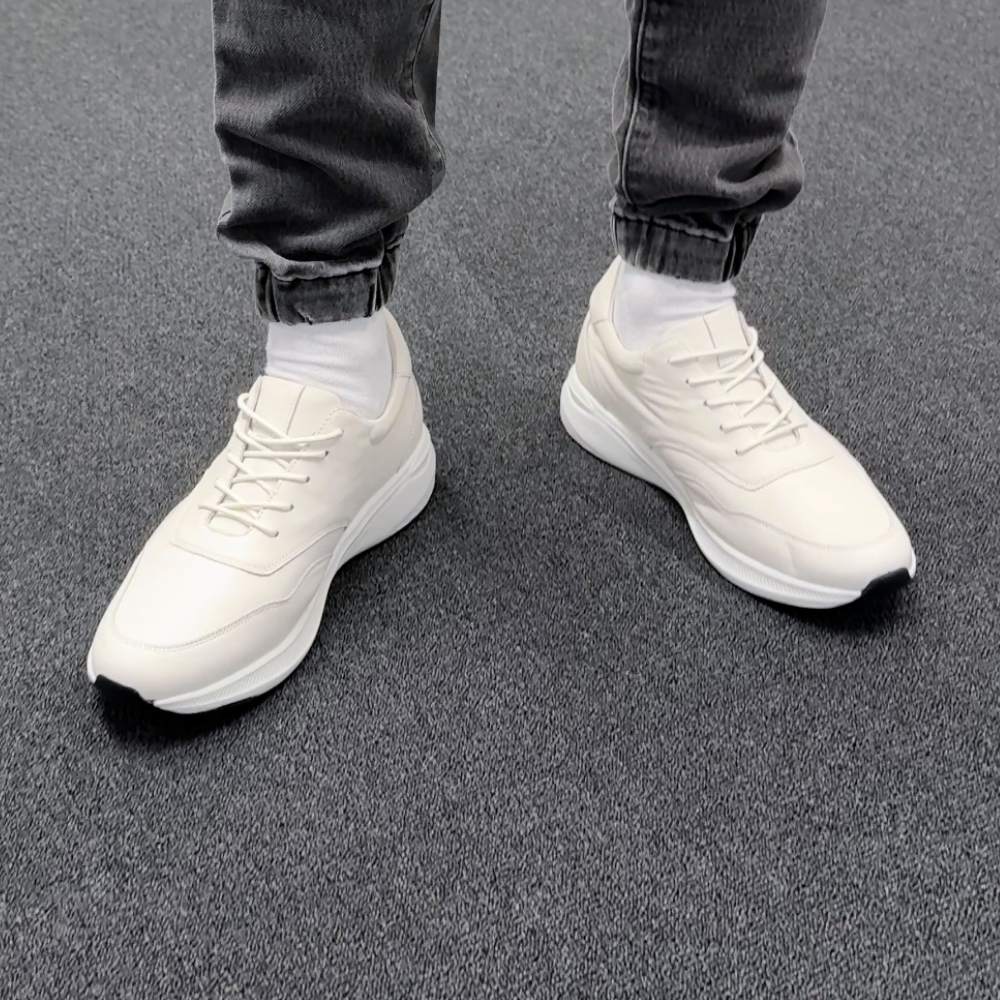 White elevator height increasing casual elevator sneakers worn with dark jeans