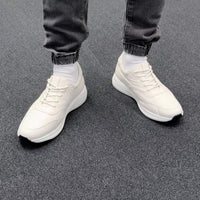 White elevator height increasing casual elevator sneakers worn with dark jeans