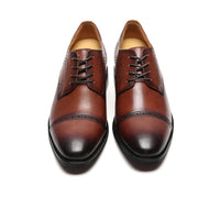 Close-up of rich dark brown premium cow leather on Mr. Mak Derby shoes, showcasing quality craftsmanship, brogue detailing, and durable rubber outsole for formal wear.